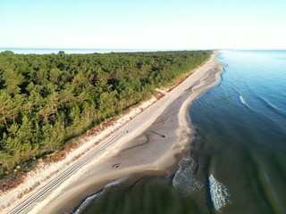High altitude aerial view of secluded coastal bay with yacht anchored near forested shoreline