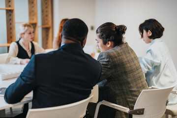 A scene of business colleagues engaged in a team meeting, actively discussing strategies and...