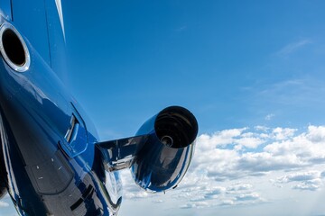 Rear view of business jet engine under a bright blue sky, photographed close-up with partial...