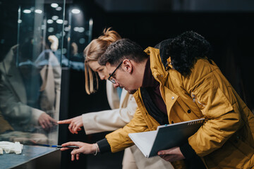 Two individuals closely inspecting an exhibit beneath glass showcasing fossils or artifacts, reflecting curiosity and academic focus © qunica.com