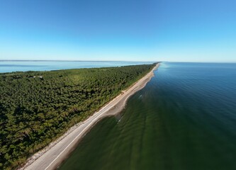 Breathtaking aerial panorama of curved coastline with forest headland jutting into turquoise sea