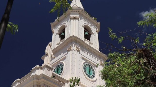 Upward view from the middle of the tower of Our Lady of Mercy Church in Corrientes Capital, Argentina. The dome, cross, clock, and bell tower are visible in detail.
