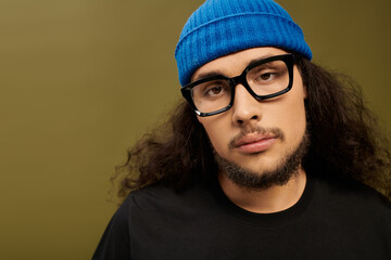 Charming young man with beard and glasses in casual attire enjoys creative expression indoors