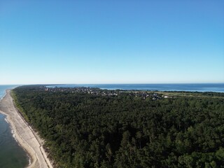 Breathtaking panoramic aerial view of coastal town nestled between dense forest and pristine beach