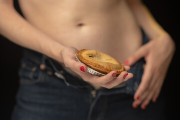An artistic image features a pie resting against a bare midriff, merging human form with culinary...