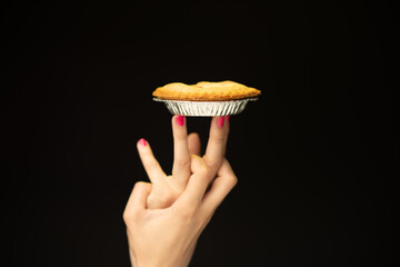 A playful hand balancing a pie on its fingers against a stark black backdrop, highlighting...