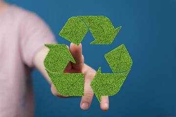 Hand interacting with a green grass recycling symbol. Eco-friendly concept.