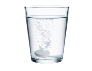 A dissolving effervescent tablet releases bubbles in a clear glass of water.