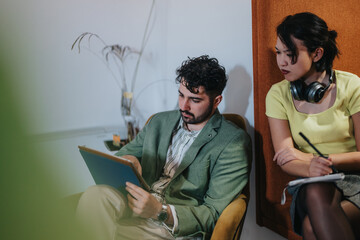 Two coworkers engage in a constructive discussion, with one writing notes and the other...