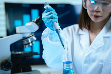 A female scientist conducts research in a modern laboratory, wearing protective gear, analyzing...