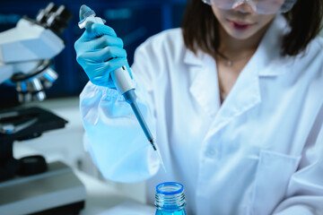 A female scientist conducts research in a modern laboratory, wearing protective gear, analyzing...