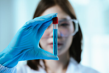 A female scientist conducts research in a modern laboratory, wearing protective gear, analyzing...