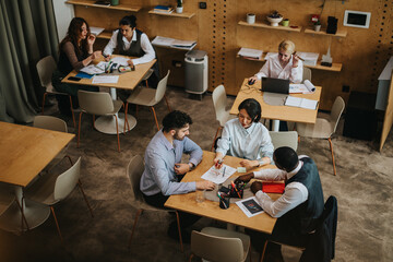 A group of people actively collaborating in a stylish co working environment, engaging in...