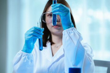 A female scientist conducts research in a modern laboratory, wearing protective gear, analyzing...