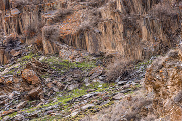 Eroded sedimentary rocks with sparse vegetation in mountainous Kyrgyzstan region