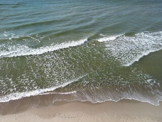 Gentle waves washing sandy beach creating soft foam patterns in natural rhythmic motion