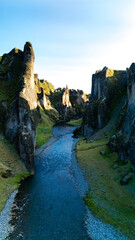 A breathtaking view of a canyon in Iceland, showcasing jagged cliffs and a tranquil river flowing...