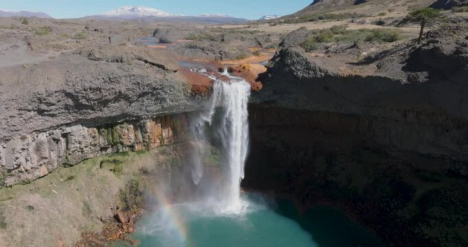 Epic aerial view of Salto del agrio waterfall plunges into a turquoise pool and rainbow peeking out. Neuquen, Argentina