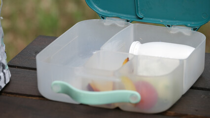 Open Lunchbox with Fruits and White Bottle