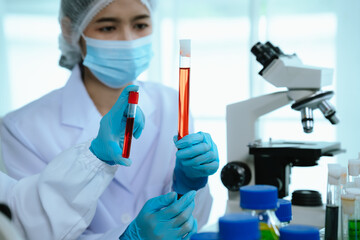 A female scientist in protective gear works in a sterile laboratory, conducting research and...