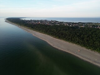 Dramatic aerial perspective of curved coastline with dark waters and forested peninsula extending...