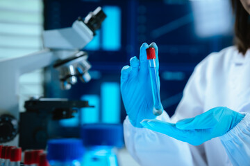 Scientists in lab coats and gloves pour blue liquid from one test tube to another to perform...