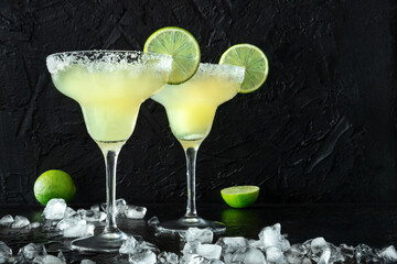 Margarita cocktail in the classic glasses, side view on a black background, with ice. Summer drinks...
