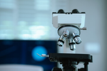 Close-up of a laboratory microscope with high-precision lenses, set against a background of digital data charts, symbolizing scientific research, innovation, and medical technology advancement.