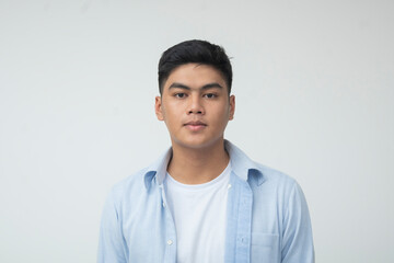 Young Filipino man in a studio setting maintains a neutral expression, staring calmly ahead with...