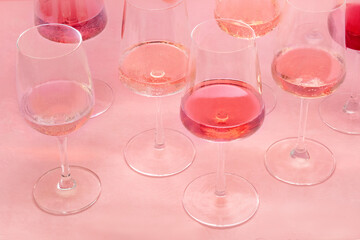 Rose wine, a variety of hues and tints, on a pink background, many wine glasses, summer party