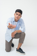 Southeast Asian man kneels on one knee while extending one hand forward with asking for help facial...
