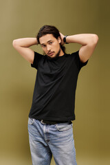 Handsome young bearded man posing against a warm olive green background with relaxed confidence