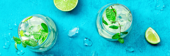Lime lemonade, or limeade, in a glass with lime, mint, and ice. Fresh summer Mojito mocktail or cocktail, with ingredients, overhead flat lay shot