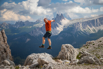 Young happy man high jumping on rocks in the Dolomite mountains.