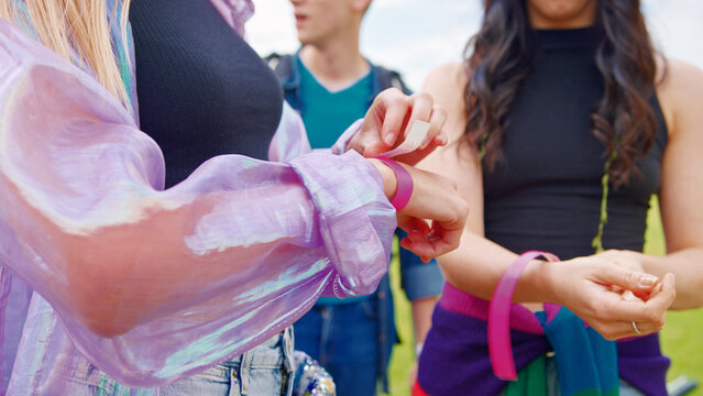 Close Up Of Young Friends At Entrance To Music Festival Putting On Security Wristbands