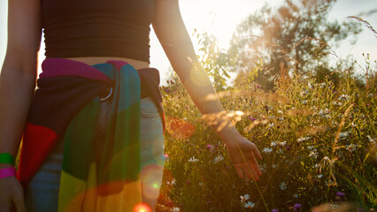 Close Up Of Woman On Camping Vacation Running Hand Through Grass And Flowers In Field