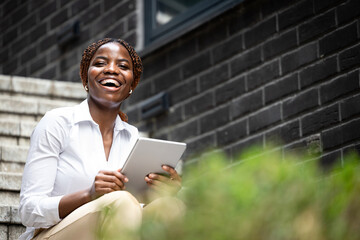Portrait of smiling African businesswoman in business suit holding tablet computer.