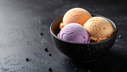 Three scoops of peach and purple ice cream served in dark speckled bowl on textured black surface, creating visually appealing and colorful dessert presentation