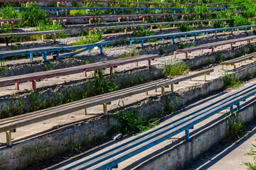 Weathered benches in overgrown abandoned stadium during daytime