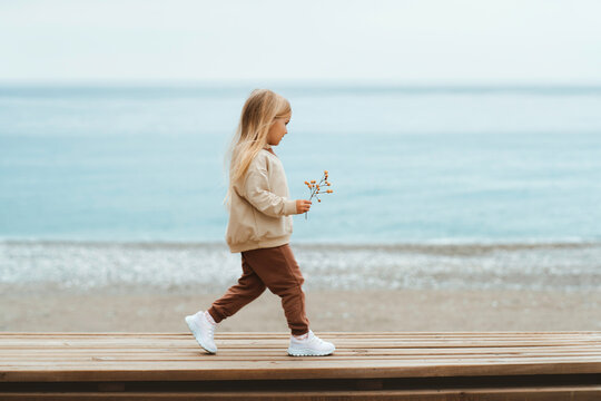 Kid girl walking on the beach cute stylish child blonde hair 4 years old on family vacations autumn season children fashion happy moments - Powered by Adobe