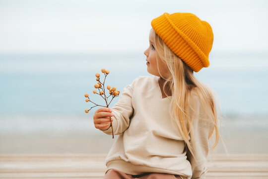 Cute child girl walking outdoor on the beach kid blonde hair 4 years old in yellow hat family travel vacations autumn season