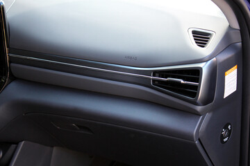 New car interior with front airbag and glove compartment. Car air conditioning system. Auto interior detail. Car ventilation close-up. Car glovebox and airbag.