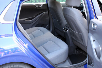 Electric car rear seats. Blue electric vehicle  interior. The rear seat of a luxury electric car with grey textile. The interior of the new car is made of gray fabric. Blue modern vehicle interior.