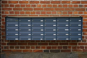 Metallic mailboxes mounted on a historic red brick wall