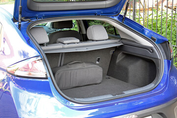 Clean, open empty trunk in blue car close up. Empty trunk of a modern blue car. Car boot is open. Modern electric car with open empty trunk. Open luggage carrier of vehicle close up.