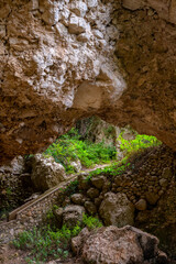 “Grotta di Matromania“ is a natural cave and historic monument on the east coast of Capri island (Italy) near the “Arco Naturale“. Green vegetation, limestone rocks and old stairway.