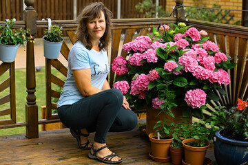 Woman crouching beside a floral display on her decking.