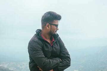 Contemplative man at Nandi Hills, Karnataka, India.  Profile view against a misty landscape.