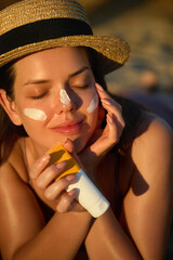 Woman is applying a facial sunscreen product. Cream, moisturizer and facial woman in skincare,...