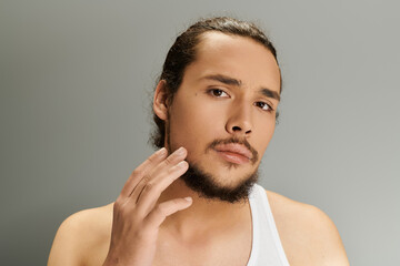 Handsome young bearded man poses confidently against a neutral backdrop